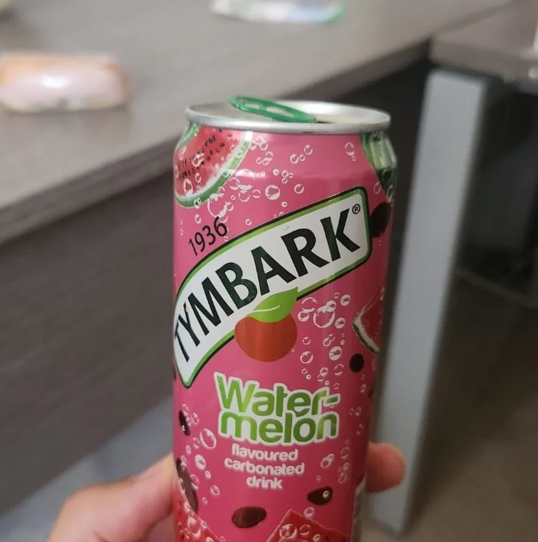 The original phone photo: a drink can held in one hand in an office